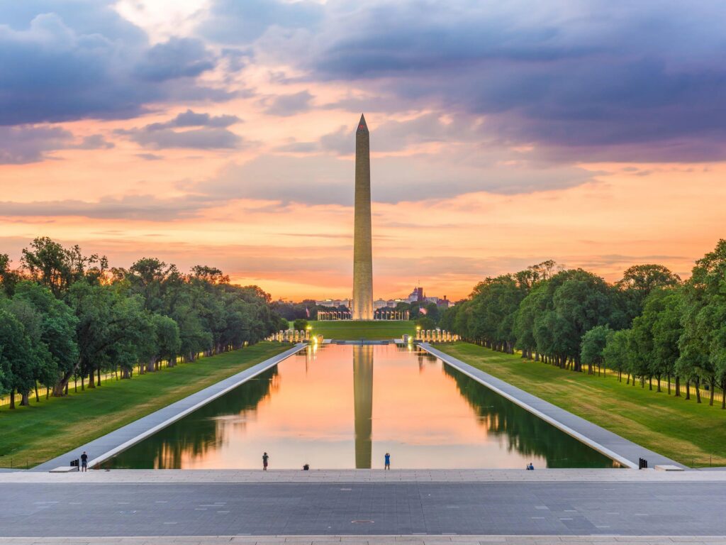 Illuminated Washington Monument reflected in the National Mall Reflecting Pool after sunset.